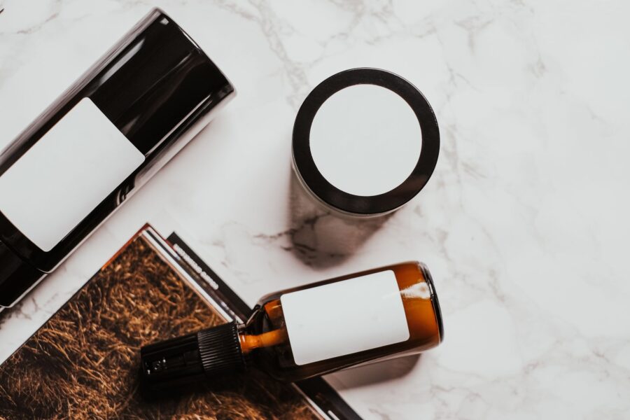 Minimal bathroom counter arranged for an acne management routine with gentle cleanser, light hydrators, and sunscreen, plus a small notebook and pen for tracking